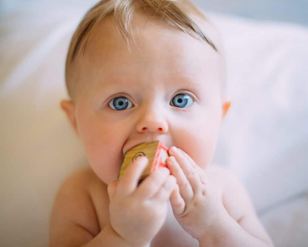 bébé mâchant un cube en bois